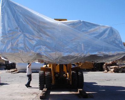 silver tarp over a Caterpillar Bull Doze being lifted in the air